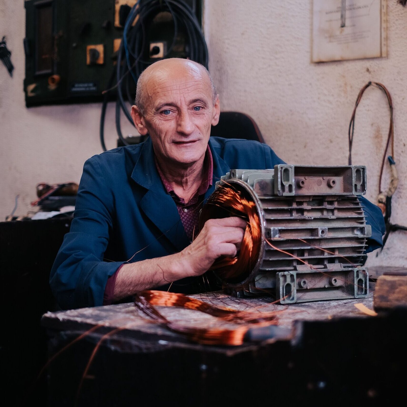 A mechanic repairs an alternator in an industrial workshop. Expertise in vehicle parts repair.